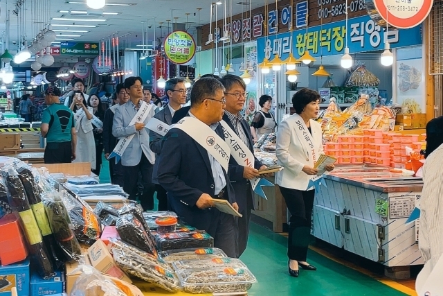 우리은행이 18일 강원도 속초시에서 속초관광수산시장 상인회와 장금이 결연을 체결했다. 협약식에 참석한 관계자들이 시장에서 보이스피싱 예방 가두캠페인을 진행하고 있다./우리은행