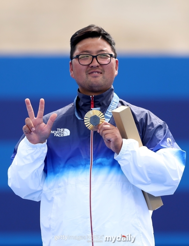 파리올림픽 남자 양궁 개인전 정상에 오른 김우진이 시상식에서 금메달을 들고 손가락으로 3관왕 달성을 의미하는 세리머니로 포즈를 취하고 있다./게티이미지코리아