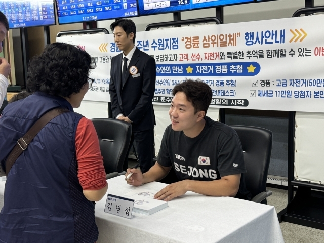 경륜경정총괄본부 수원사업소에서 김명섭(오른쪽)이 고객과 소통하며 사인을 해주고 있다. /경륜경정총괄본부 제공