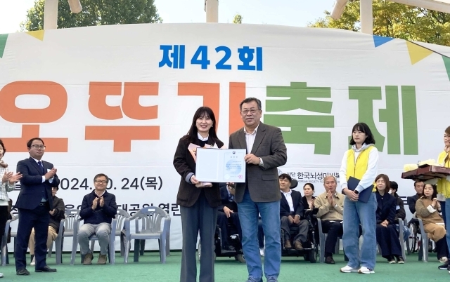 지난 24일 서울어린이대공원에서 개최된 오뚜기 축제에서 김정우 한국뇌성마비복지회 회장이 윤보람 유니클로 서스테이너빌리티 매니저에게 보건복지부 장관 표창을 수여하고 있다./유니클로