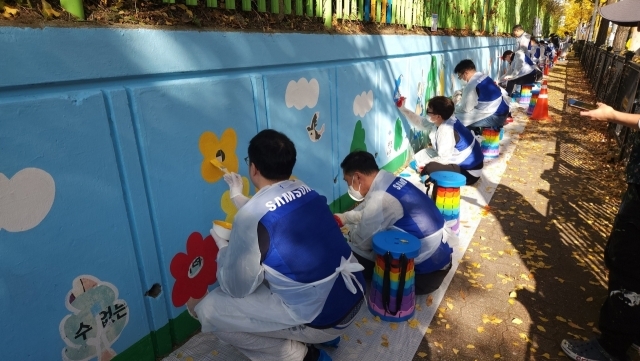 삼성전자 임직원들이 12일 수원시 권선구 구운초등학교에서 벽화 그리기 봉사 활동에 참여하고 있다. /삼성전자