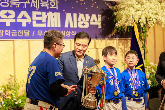 황윤제 감독(가장 왼쪽)이 선수들과 함께 우승컵을 전달하고 있다. /성북구유소년야구단 제공